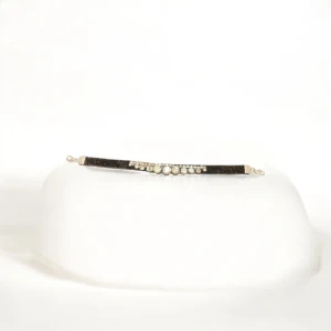 Glittrigt armband med stenar - Elegant armband med en rad av glittrande stenar på en svart rem. Perfekt för att ge en touch av glamour till din outfit. Armbandet har en smidig passform och är lätt att bära.