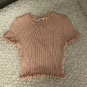 Rosa ribbad topp från Zara - Säljer en söt rosa ribbad topp från Zara. Den är kortärmad och croppad med volangdetaljer💓