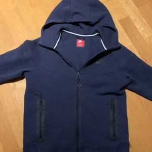 Mörkblå Niketech  - Säljer en mörkblå Niketech som är nästan aldrig använd(känns som en ny!). Passar M och L, köpte den för 1200.