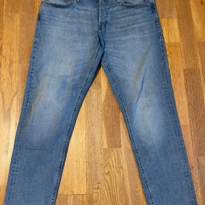 Jack & Jones jeans - Ljusblåa tapered fit jeans från Jack & Jones (Mike modellen), storlek 32/30. Mycket bra skick på dom, inga tecken på användning. Kontakta mig vid frågor!