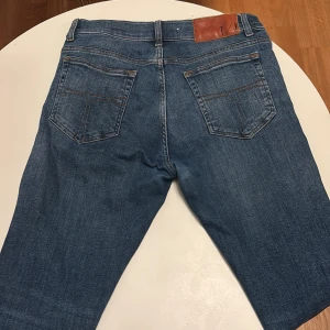 Blå Tiger of Sweden jeansbyxor - Snygga blå jeansbyxor från Tiger of Sweden med klassisk femficksdesign och knappgylf. Perfekta för en avslappnad stil. Märkesdetalj på baksidan av midjan. Jätte bra skick, 31 32