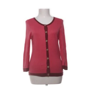 Rosa kofta från Juicy Couture - Säljer en snygg rosa kofta från Juicy Couture med mörkare kantdetaljer och knappar framtill. Koftan är tillverkad i en mjuk blandning av bomull, silke och kashmir för extra komfort. Perfekt för att lägga till en färgklick i garderoben!