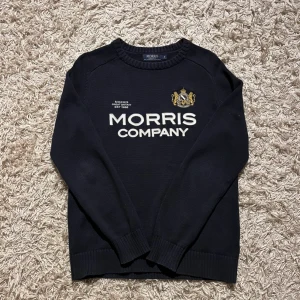 Svart tröja från Morris - Säljer en stilren svart tröja från Morris med broderad logotyp och text på framsidan. Tröjan är tillverkad i 100% bomull och har långa ärmar samt ribbade muddar vid ärmslut och nederkanter. Perfekt för en klassisk look. Mycket bra skick utan några defekter i storlek M. Fraktas antigen samma dag som köp eller dagen därpå💯🙌