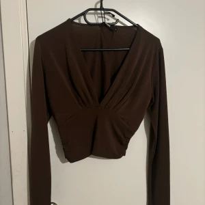 Brun långärmad topp - Snygg brun långärmad topp med djup v-ringning och omlott-design. Använd fåtal gånger! I storlek S och från bikbok 🌸