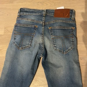 Blå, snyggt slitna jeans, Tiger - Snygga blå jeansbyxor från Tiger, klassiska smala, naturligt sliten look. Helt oanvända. Size 27/32. 