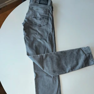Grå Replay Anbass jeans - Snygga grå jeans från Replay, modell Anbass med slim fit. De har en klassisk femficksdesign och en knappgylf. Perfekta för en stilren look. Hör av er vid funderingar, byxorna är i gott skick!