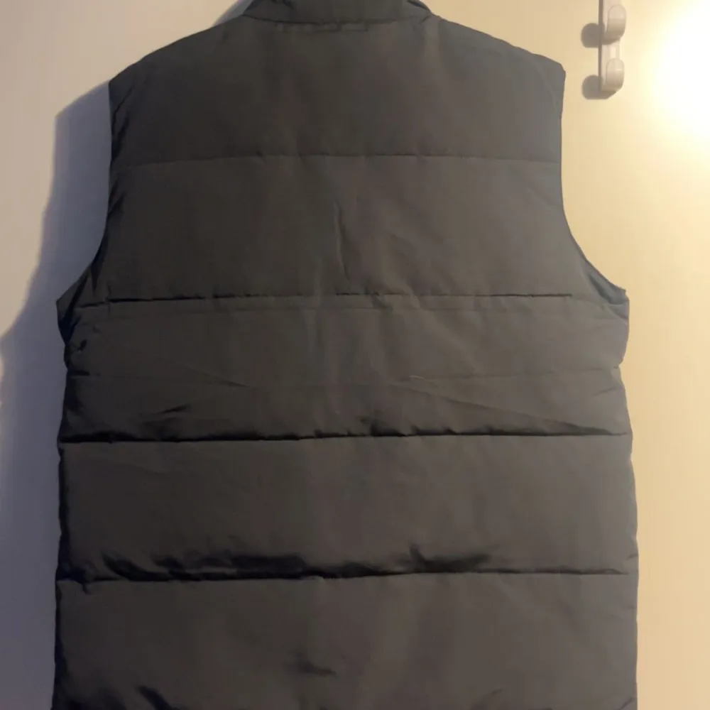 Säljer en stilren grå dunväst från Canada Goose med deras ikoniska logga på bröstet. Västen har knappar framtill och två praktiska fickor. Perfekt inför hösten och dessutom helt ny väst i storlek M. KAN KÖPAS ENDAST GENOM VINTED ELLER POST då det ej går att sälja på denna app. Och mitt vinted användarnamn är - Glass3451 . Takit.