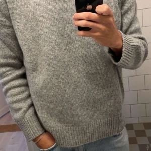 Tröja i Ullblandning Grå Arket - Säljer en stilren grå stickad tröja från Arket med rund hals och ribbade muddar. Perfekt för kyligare dagar och enkel att matcha med outfits. Tröjan kommer i storlek XS passar även S. Tröjan är i nyskick knappt använd. Nypris 790kr