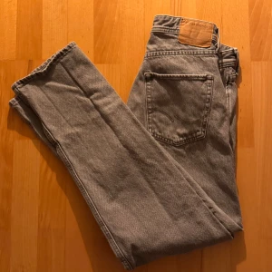 Grå jeansbyxor - Snygga grå jeansbyxor från Jack&Jones med en relaxed passform. De har en klassisk design med fem fickor och en knappgylf. Perfekta för en avslappnad stil. Strl 31/34