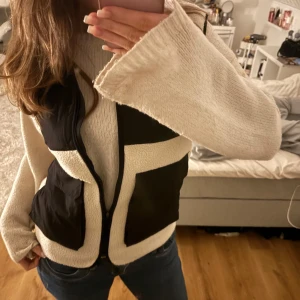 Svart och beige fleeceväst - Säljer en snygg svart och beige fleeceväst med dragkedja. Västen har stora fickor och en mysig design som passar perfekt för kyligare dagar. Perfekt för lager-på-lager-stil! Passar snyggt till antingen en afterski outfit eller bara en vardaglig outfit! Köpt från hm barnavdelning i storlek 164/170 och passar en S/M. Västen finns inte att köpa längre! Tveka inte att höra av dig vid frågor!💞💞