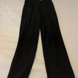 Svarta byxor med hög midja - Snygga svarta byxor med hög midja och rak passform. Perfekta för en stilren look. Midjemått är W30 och längd L32.