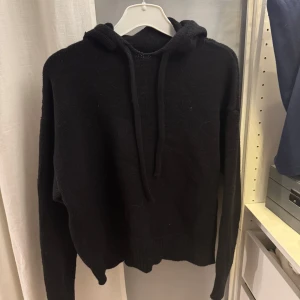 Svart stickad hoodie från Zara - Säljer en svart stickad hoodie från Zara. Den har en mysig huva och långa ärmar, perfekt för kyliga dagar. Enkel och stilren design som passar till det mesta. Perfekt för en avslappnad look.