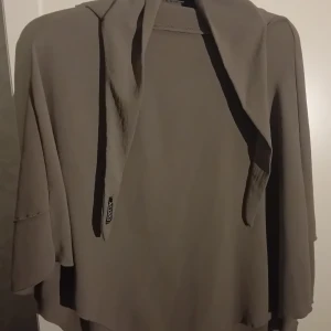 Beige/gråaktig khimar(en slags sjal) från Neyssa - Säljer en två lagrig beige khimar från Neyssa (en fransk onlinebutik).Den har en lös passform och är perfekt för att använda under alla säsonger. Khimaren har en enkel design utan mönster och är tillverkad i ett mjukt material. 