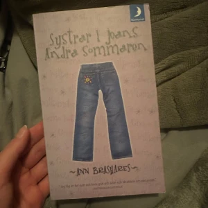 Systrar i jeans: Andra sommaren - Boken 'Systrar i jeans: Andra sommaren' av Ann Brashares är en del av en populär ungdomsserie. Omslaget visar ett par jeans mot en ljus bakgrund. Perfekt för dig som gillar vänskap och sommaräventyr.