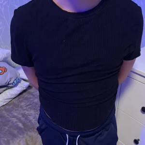 Svart kortärmad topp med öppen rygg - Snygg svart topp med korta ärmar och en trendig öppen rygg med knytning. Perfekt för en stilren look.