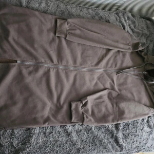 Brun långärmad jacka med dragkedja - Säljer en brun långärmad jacka med dragkedja. Jackan har ribbade muddar vid ärmsluten och en enkel design som passar till många tillfällen.