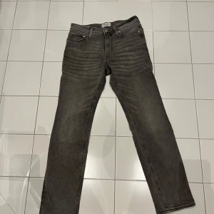 Grå jeans från Jack & Jones - Snygga grå jeans från Jack & Jones i modellen 'Replay Clark'. De har en klassisk femficksdesign och en bekväm passform. Perfekta för en stilren look. 