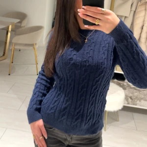 Mörkblå stickad tröja - Säljer en snygg mörkblå stickad tröja med kabelstickat mönster. Har använt den ett fåtal gånger och den kommer inte till användning 