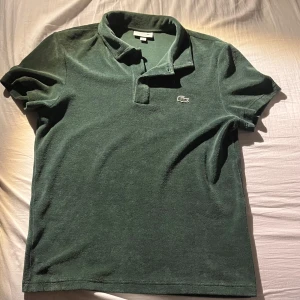 Grön pikétröja från Lacoste - Tjena! Säljer en snygg grön pikétröja från Lacoste i bomull. Tröjan har korta ärmar och en klassisk krage med knappar. Perfekt för en stilren och avslappnad look. Priset är inte hugget i sten och kan gå ner i pris vid en snabb affär.