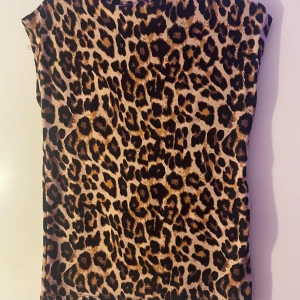 Leopardmönstrad topp från 157 - Snygg leopardmönstrad topp från 157 i storlek S. Toppen har en tight passform och är ärmlös, perfekt för en trendig look. Den är gjord i ett mjukt och bekvämt material. Endast använd en gång, ingen prislapp kvar