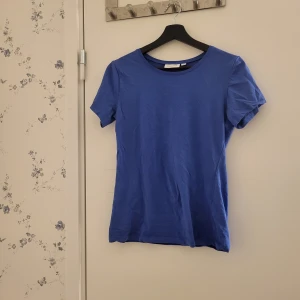 Blå t-shirt - Snygg blå t-shirt i bomull med rund hals och korta ärmar. Perfekt för en avslappnad stil. Lite skrynklig på bilden. Har använt 2 gånger används inte längre. Köpt för 199 från kappahl säljer för 99kr pris kan diskuteras 