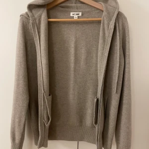 Beige hoodie från Soft Goat - Säljer en stilren grå hoodie från Soft Goat i kashmir. Tröjan har dragkedja och två fickor framtill, samt en mysig huva med dragsko. Perfekt för kyliga dagar! pris diskuteras!