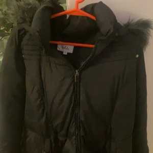 Svart dunjacka från Isolde - Snygg svart dunjacka från Isolde med pälskantad huva. Jackan har dragkedja framtill och är perfekt för vintern. 