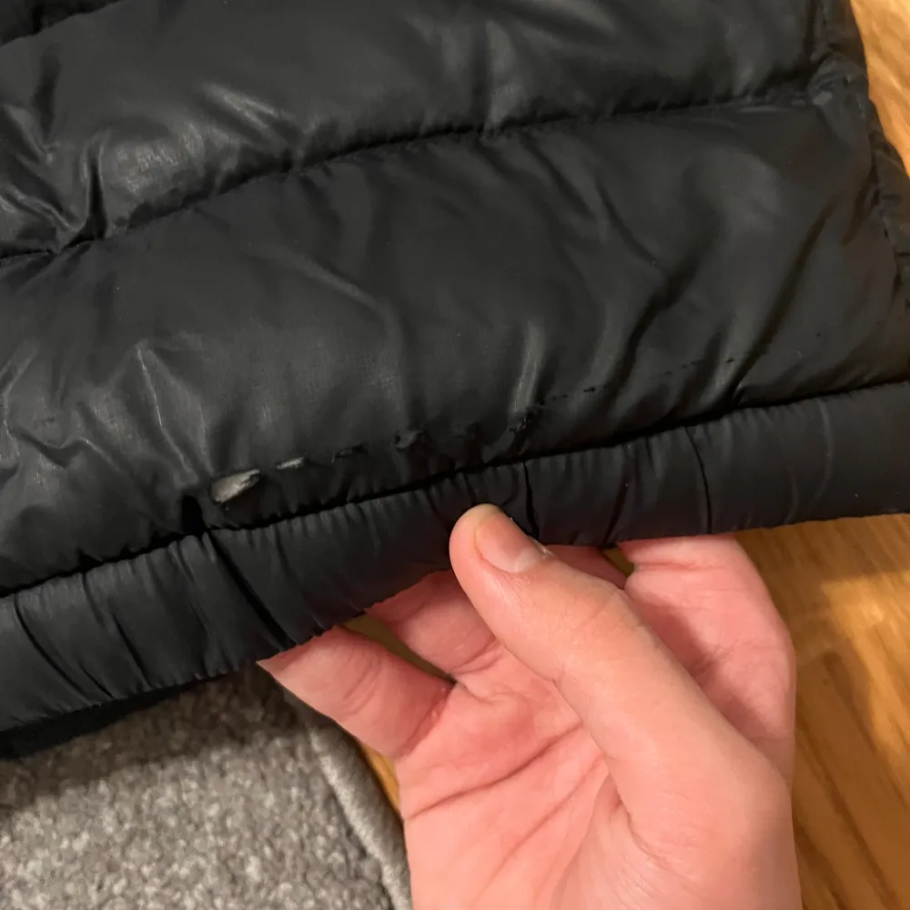Säljer en svart dunjacka från Peak Performance. Jackan har en dragkedja framtill och är långärmad med elastiska muddar. Perfekt för kyliga dagar med sin pufferdesign som håller värmen. I den sista bilden är det ett litet hål som man inte märker jackan är mörkblå och man ser inte den lilla hålet på den sista bilden eftersom den är så pass liten den med flera hål märker man absolut ingenting som du kan se se på bilderna när jag visar back sidan av jackan. Takit.