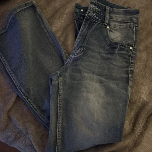 Blå jeans med broderade bakfickor - Snygga blå jeans med hög midja och broderade detaljer på bakfickorna. 