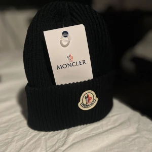 Moncler mössa  - Den väldigt klassiska Moncler-mössan, den kan man aldrig gå fel med, när man tar på sig mössan blir man ultra rizz 🤫🧏, och alla får plats med den då den är one size fits all, väska och tagg ingår, kontakta mig gärna ev. du har ett erbjudande eller en fråga🫡