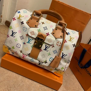 Louis Vuitton vintage väska  - Snygg vit handväska från Louis Vuitton med ett färgglatt monogrammönster. Väskan har läderdetaljer och en dragkedja upptill. Perfekt för att ge din outfit en lyxig touch. Kvitto finns och den är knappt använd. Priset har ökat i värde sedan jag köpte den. 