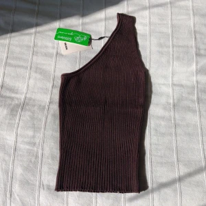 Oanvänd brun ribbad one shoulder top - chokladfärgat ribbstickat linne - storlek S - Brun ribbstickad one shoulder topp. Mjuk och stretchig - sitter väldigt fint på. Oanvänd med tags kvar. 80% viskos och 20% nylon. Storlek S. 