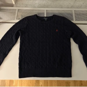 Ralp lauren kabelstikad  - En fräsch ralp lauren tröja i marinblå färg med röd logga knappt använd och är riktigt bra tröja inför vinter vid fler funderingar skriv i dm 