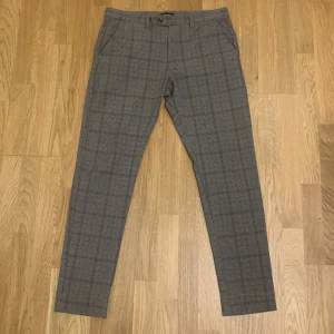 Jack & Jones rutiga kostymbyxor  - Kostymbyxor i rutigt mönster som ser ut som burberry. Byxorna är tillverkade med ett mjukt och bekvämt material. Nyskick, bara använt en gång för att ta bild. Det är bara att skriva om ni har frågor. Storleken 33/32 motsvarar M. Orginalpris 600 kr.