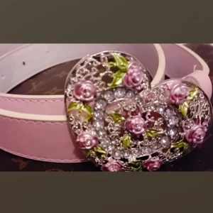 Hjärtformad bling bling skärp med söta detaljer - Rosa och silvrigt hjärtformat bälte med fina detaljer som rosor och strass stenat däri:) 105 Cm långt