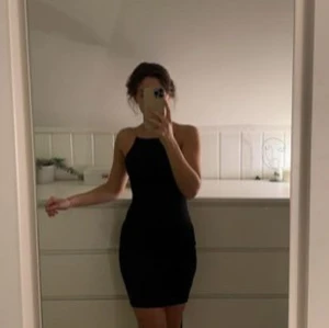 Svart klänning med kedjeband - Säljer en elegant svart klänning med kedjeband som ger en lyxig touch. Klänningen är tight och har en stilren design som passar perfekt för festliga tillfällen. Den är ärmlös och har en rak halslinje. Köpt för 299kr, och den är endast använd EN gång.