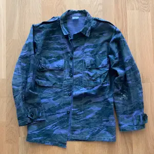 Vintage blå camouflage fieldjacka. Köpt i Paris. Skick 9/10. Storlek small. Den har en färgfläck på vänster underärm (visas i annons). Supersnygg och passar till allt, perfekt till hösten. 