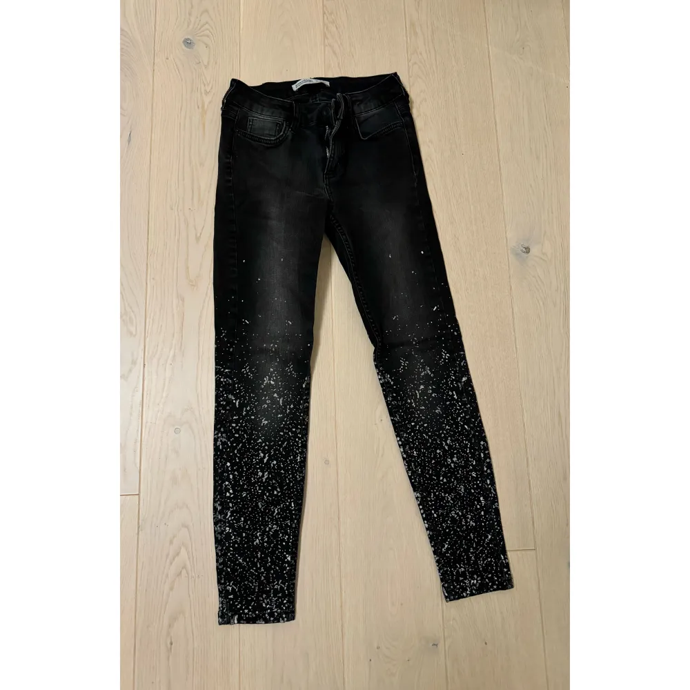 Ett par svarta skinny jeans från Zara med ett coolt vitt stänkmönster längst ner. De är tighta och har en låg midja, perfekt för en trendig look. . Jeans & Byxor.