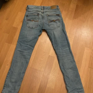Nudie jeans - Nudie Jeans i storleken 30 30. Jeansen är använda men i bra skick. De har 2 lagningar som syns på bild därav det låga priset. Dem är dock inte särskilt synliga. Modellen är grim trim