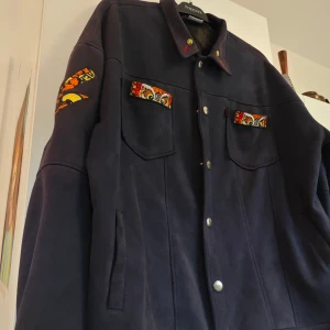 Drake jacka  - Blå jacka i mjukt suede-liknanfe material. Broderade detaljer 