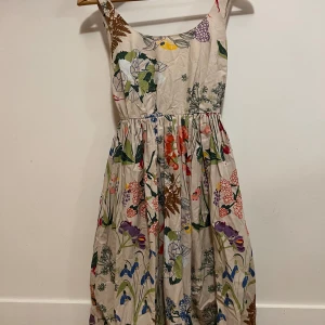 Blommig sommarklänning med knytband - Säljer en superfin blommig klänning perfekt för sommaren!  Bandet i midjan ger fin passform och gör även så att den passar fler storlekar. Går att både knyta fram och bakåt. 