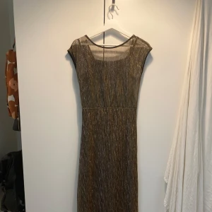 Glittrig balklänning - Superfin fotsida klänning perfekt för höstens baler eller fester. Svart/guld/silver. Använd en gång och i jättebra skick. Från Vero Moda, storlek S.
