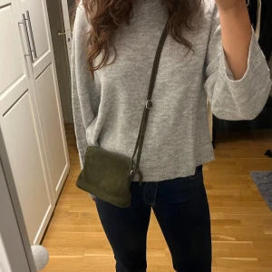 Grön axelväska - Grön axelväska i mocka material. Har använt ett par gånger men är i väldigt bra skick och är inte sliten. Släjer pga att jag inte använder längre. (Kommer inte ihåg vart jag köpte, nypris ca 400kr) Köparen står för frakt, pris går att diskutera.