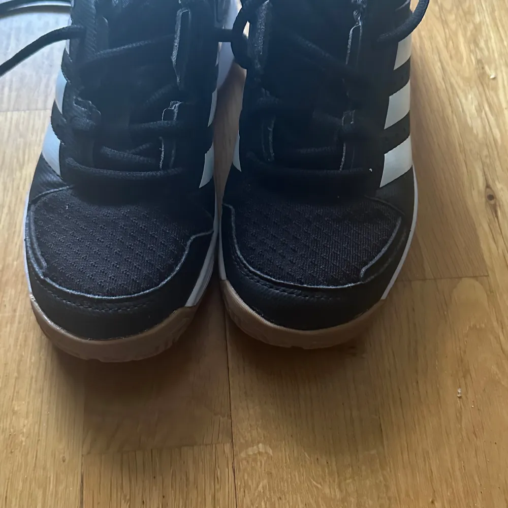 Säljer ett par snygga svartvita Adidas sneakers i mycket bra skick. De har klassiska tre ränder på sidan och en bekväm passform. Perfekta för både vardag och träning. Skorna har snörning och en slitstark sula.. Skor.