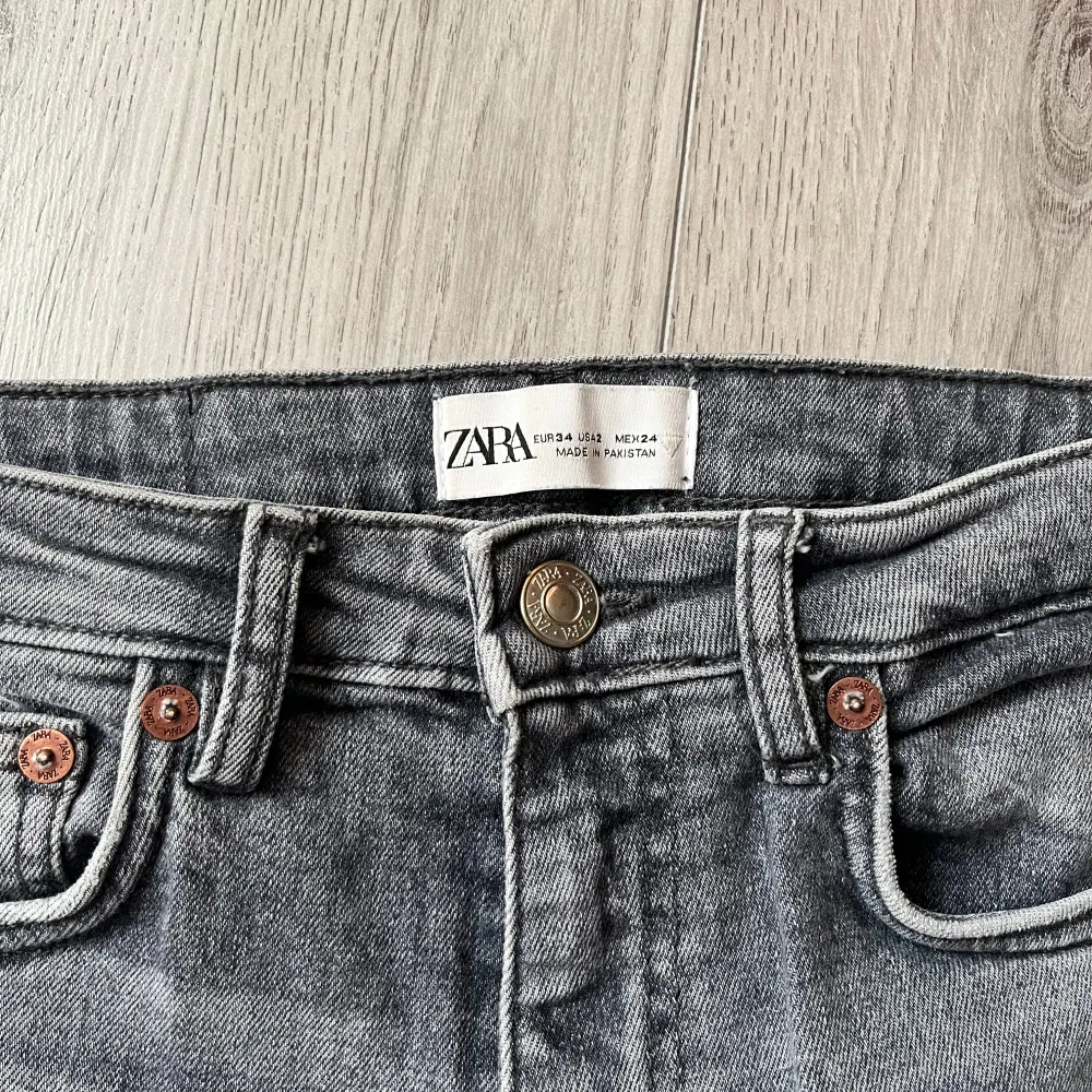 Säljer ett par grå jeans från Zara i bra skick. De är hög/mellan midjade med slitna detaljer på knäna och slits nere vid fötterna. Perfekta för en casual look! Dock har ”örat” på sidan av midjan lossat lite grann men det är inget som syns. Säljer de för de är för små för mig. . Jeans & Byxor.