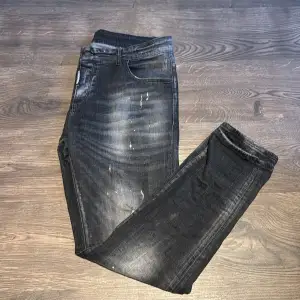 Säljer ett par svarta jeans med coola slitningar och en lätt blekt look. De har en klassisk femficksdesign och är perfekta för en avslappnad stil. Passar både till vardags och fest. Sköna och trendiga!