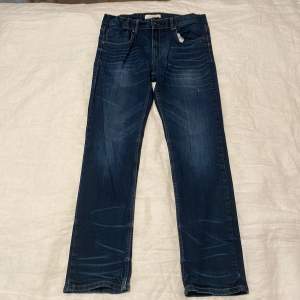 För barn (10-12år) bestäm eget pris                                              Säljer ett par snygga blå jeans från LINDCX i bra skick. De har en klassisk straight passform och är perfekta för vardagsbruk. Jeansen har en knappgylf och är tillverkade i ett slitstarkt denimtyg.