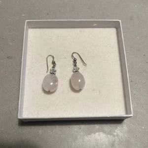 Eleganta örhängen med rosa stenar - Säljer ett par eleganta örhängen med ljusrosa stenar. De har en fin droppform och är dekorerade med små, glittriga detaljer ovanför stenen. Perfekta för både vardag och fest! 💖