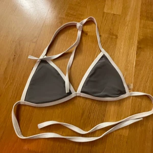 Grå och vit bikini från Zaful - Säljer en snygg grå och vit bikini från Zaful i storlek M. Den har en klassisk trekantsform med knytband i nacken och ryggen. Perfekt för sommardagar på stranden eller vid poolen. Materialet är mjukt och bekvämt, vilket gör den idealisk för både bad och solning. 🏖️