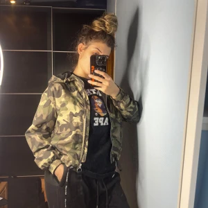 Camouflage bomberjacka från Bershka - Säljer en snygg camouflage bomberjacka från Bershka i storlek S. Jackan har dragkedja och är perfekt för höst och vår. Den är i mycket bra skick och har en cool, avslappnad stil. Passar perfekt för en casual look eller när du vill sticka ut lite extra!